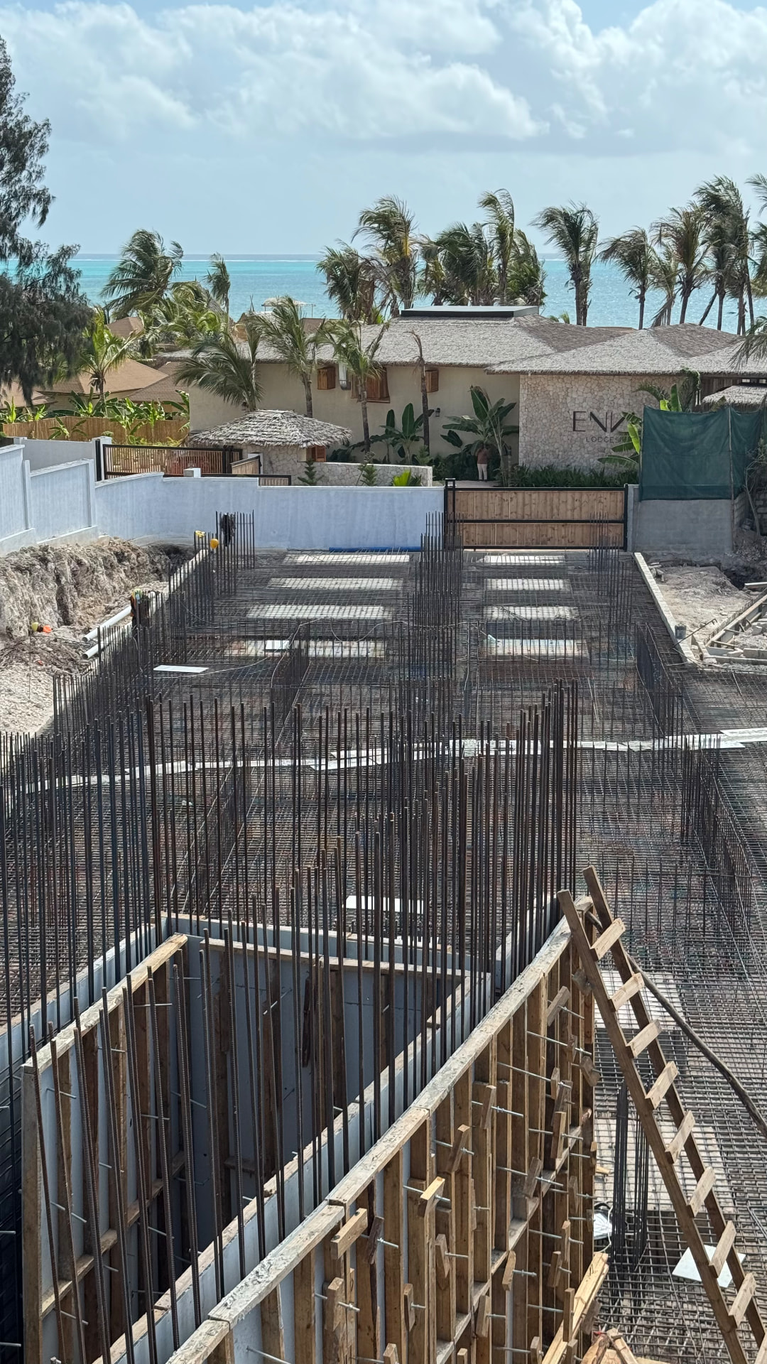 Samawa Beach Resort construction — site overview with foundation work by the beach